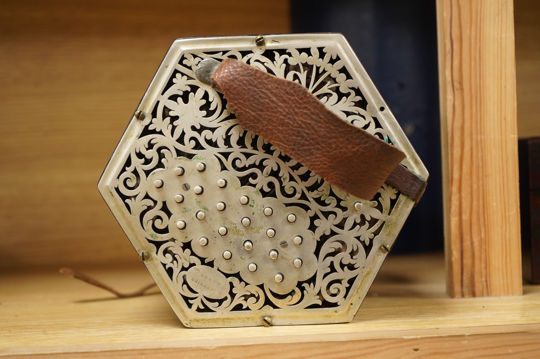 A Jeffries hexagonal concertina with pierced silvered metal ends, and gilt tooled leather bellows, maker’s mark stamped to the metal work on one end